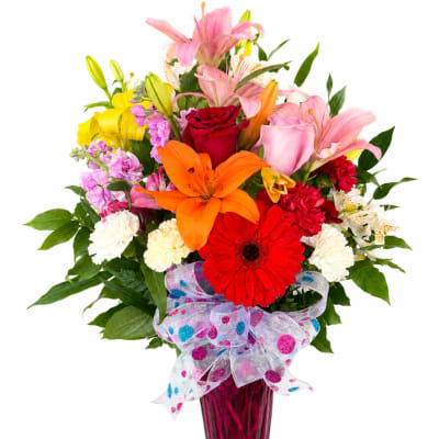 Colorful bouquet of lilies, roses, gerbera daisies, and carnations in a pink vase