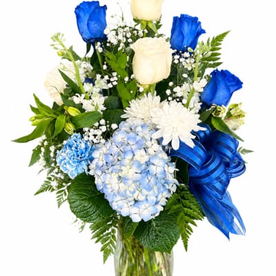 Blue and white flower arrangement in a glass vase with a ribbon