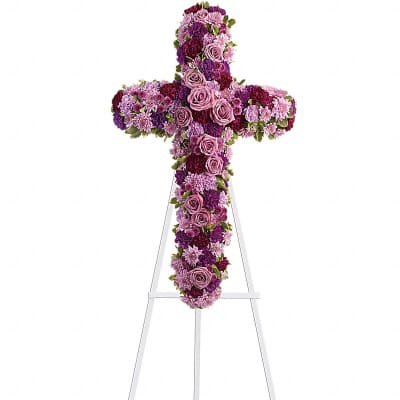Standing cross-shaped spray of pink and purple flowers on a white easel