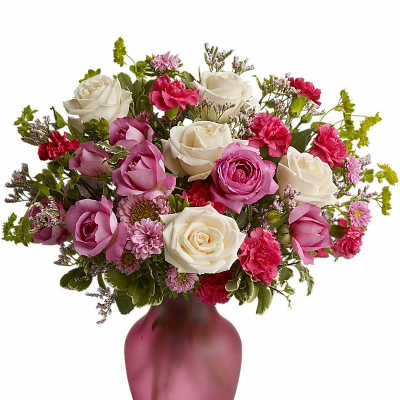 Pink and white roses with pink carnations and mums arranged in a pink frosted glass vase