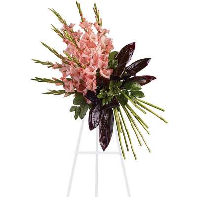 Tall standing spray with pink flower spikes and dark burgundy leaves on a white easel