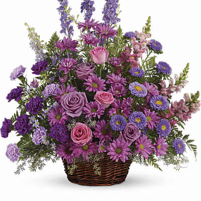 Fan-shaped basket of pink roses, lavender daisies, purple carnations and other blooms in a woven basket.