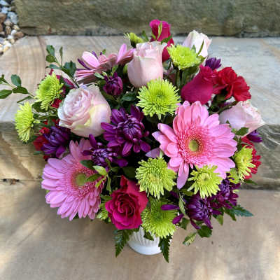 Mixed pink, purple, and green bouquet in a white vase