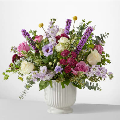 Mixed bouquet of pink, white, and purple flowers in a white vase