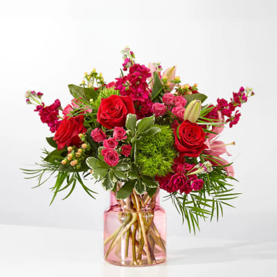 Bouquet of red and pink flowers in a pink glass vase