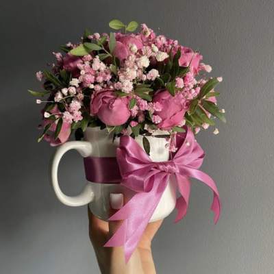 Pink rose bouquet in a white mug with a satin bow