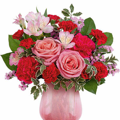 Pink roses, red carnations, and pale alstroemeria in a pink glass vase