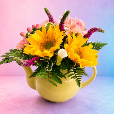 Yellow sunflowers and pink flowers arranged in a yellow teapot