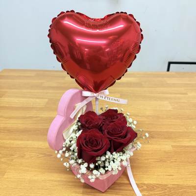 Red heart balloon above red roses in a pink heart box