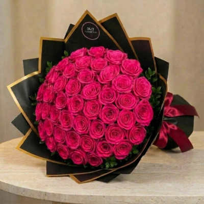 Bouquet of bright pink roses wrapped in black paper with gold trim