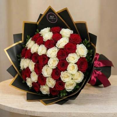 Bouquet of red and white roses wrapped in black paper with gold trim