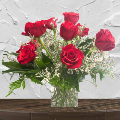 Red roses arranged in a clear glass vase with white filler flowers