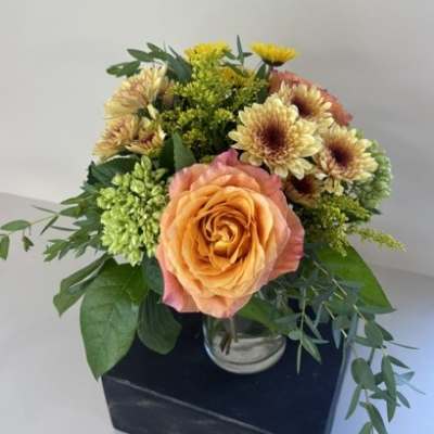 Peach rose bouquet with yellow chrysanthemums in a glass vase