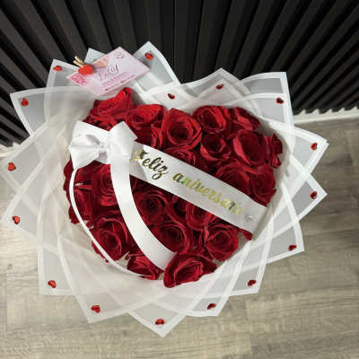 Heart-shaped bouquet of red roses wrapped in white paper with a ribbon