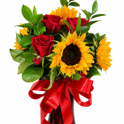 Bouquet of red roses and yellow sunflowers in a glass vase with a red ribbon