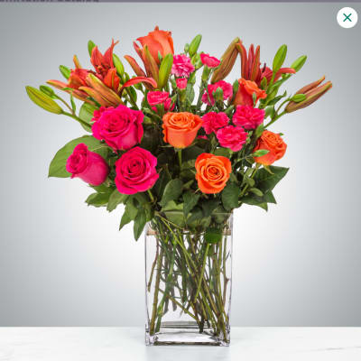 Bouquet of pink and orange roses with lilies in a clear glass vase