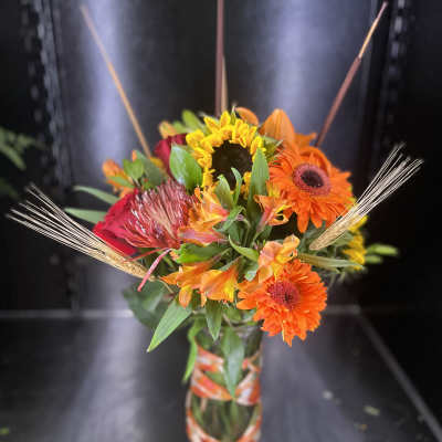 Bright mixed bouquet in a glass vase with orange and yellow blooms