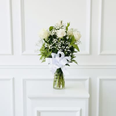 White rose bouquet in a glass vase with a white ribbon
