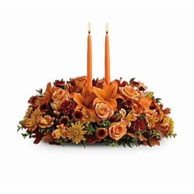 Orange floral centerpiece with two taper candles