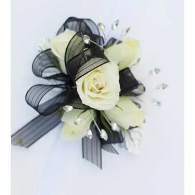 White rose corsage with black ribbon and crystal accents on a white background