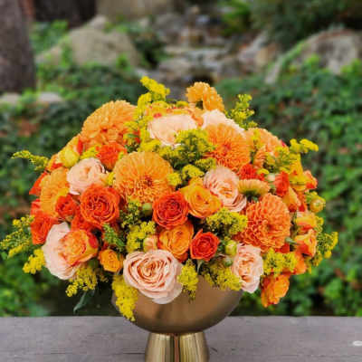 Orange and peach bouquet in a gold vase