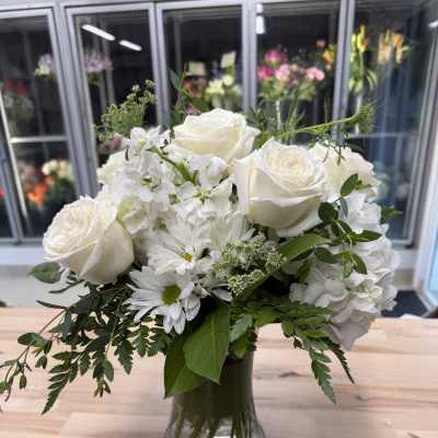 White rose and daisy bouquet in a clear glass vase