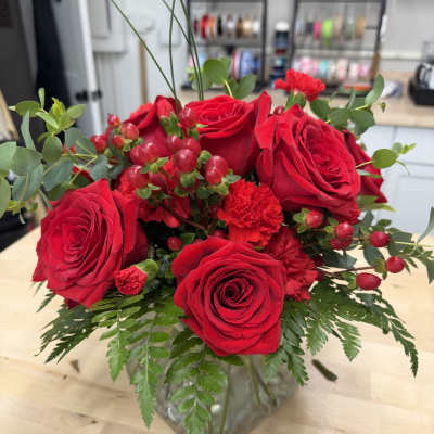 Red roses and carnations arranged in a clear glass vase