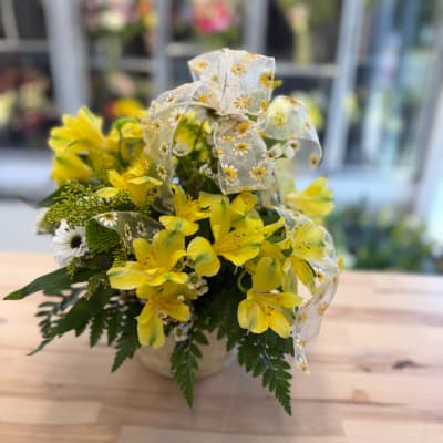 Yellow alstroemeria bouquet in a small vase with a daisy ribbon