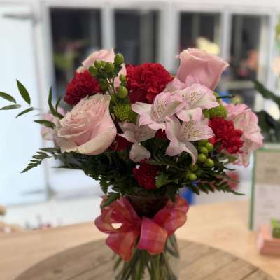 Pink and red mixed bouquet in a glass vase with a ribbon