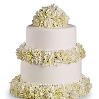 Three-tier white wedding cake with ivory floral garlands