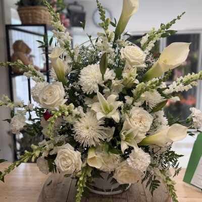 White floral arrangement with roses, calla lilies, and chrysanthemums in a vase