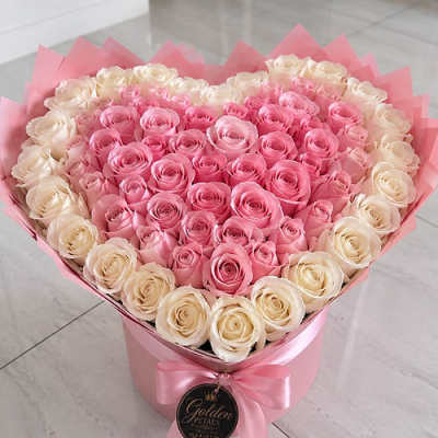 Heart-shaped bouquet of pink and cream roses in a pink box