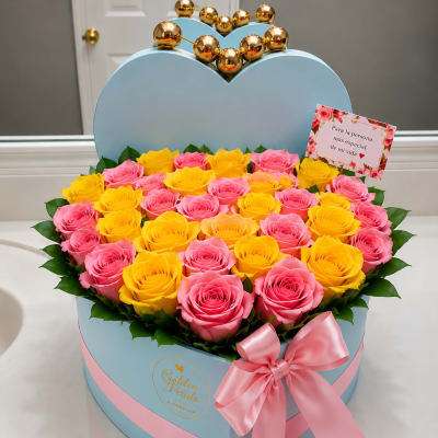 Heart-shaped box of pink and yellow roses with a pink ribbon