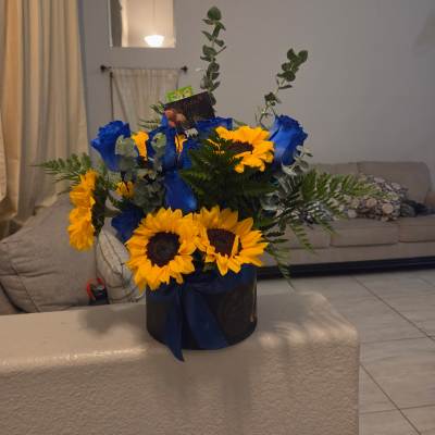 Blue roses and sunflowers arranged in a black hat box