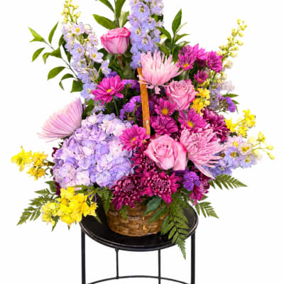 Basket arrangement of pink, purple, and yellow flowers