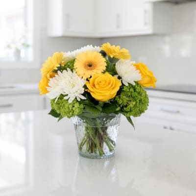 Yellow and white flowers arranged in a clear glass vase