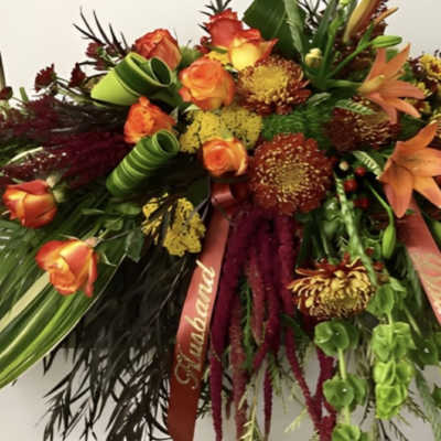 Large spray of orange roses and mixed autumn flowers with ribbons