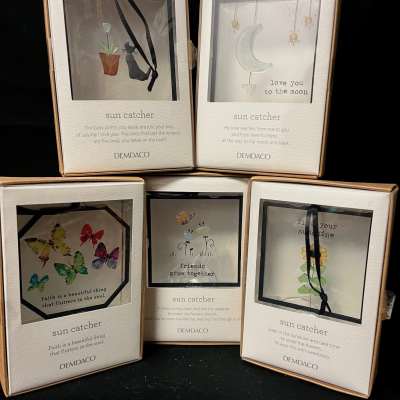 Boxes of decorative sun catchers with butterflies, moon, and flower designs