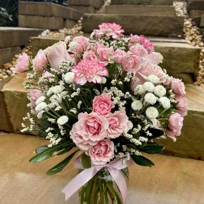 Pink roses and carnations in a glass vase with a pink ribbon
