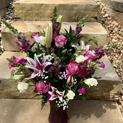 Pink and white mixed flower arrangement in a purple vase