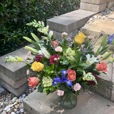 Mixed bouquet of roses, lilies, and irises in a glass vase