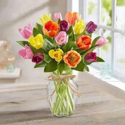 Colorful tulip bouquet in a clear glass vase with a ribbon bow