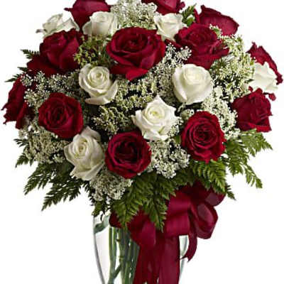 Red and white roses arranged in a clear glass vase with a red ribbon