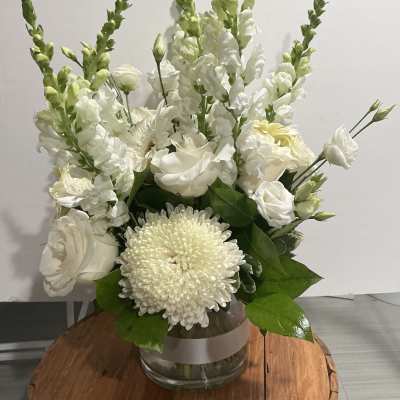White floral arrangement in a glass vase with tall snapdragons and chrysanthemums