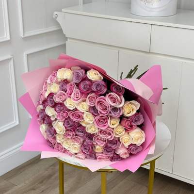 Large bouquet of pink, lavender, and cream roses wrapped in pink paper