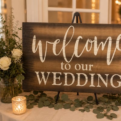 Wedding welcome sign on an easel with white roses and candles