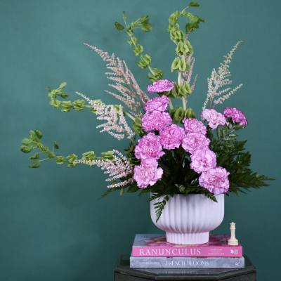 Pink carnations in a white vase with airy pink filler flowers