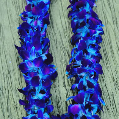 A purple and blue flower lei laid on a wood surface