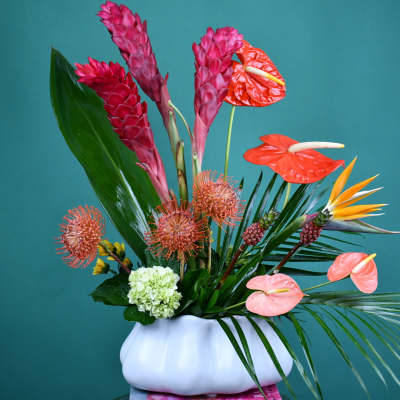 Tropical flower arrangement in a white vase with pink and orange blooms