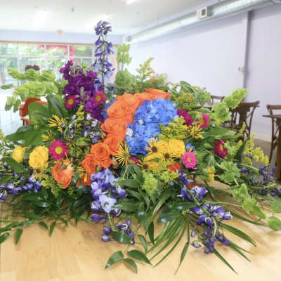 Large colorful floral arrangement with roses, hydrangeas, and purple blooms on a table